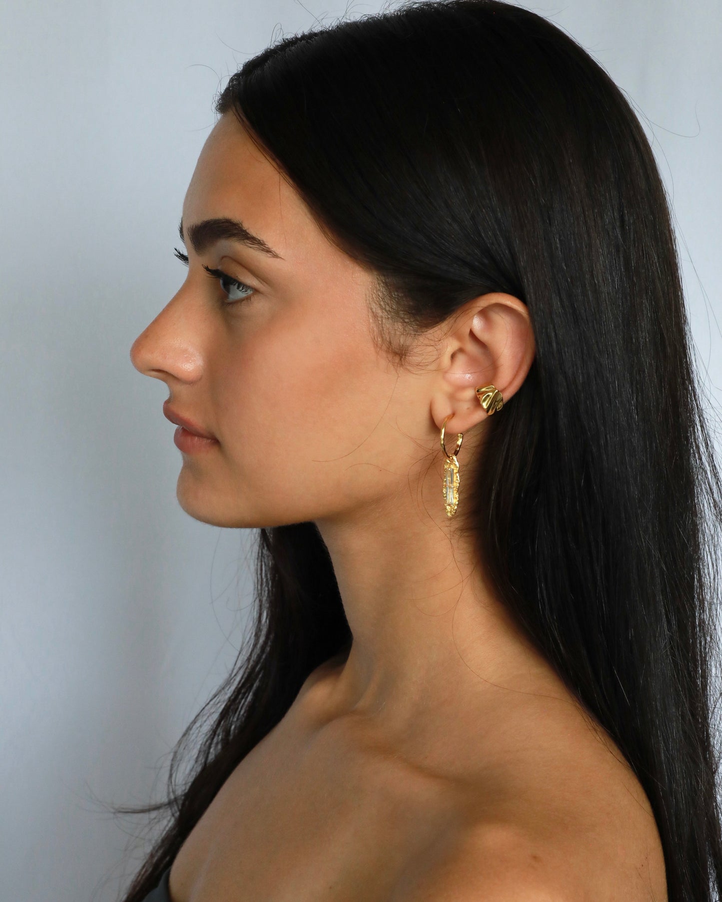 Close-up of gold plated white zircon earring on model’s ear
