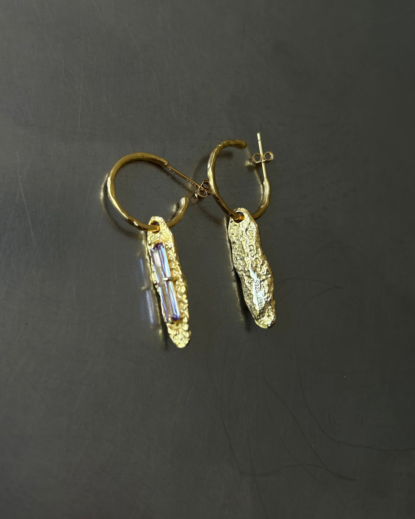 Back view of gold plated sterling silver earrings with white zircon and S925 engraving on dark background