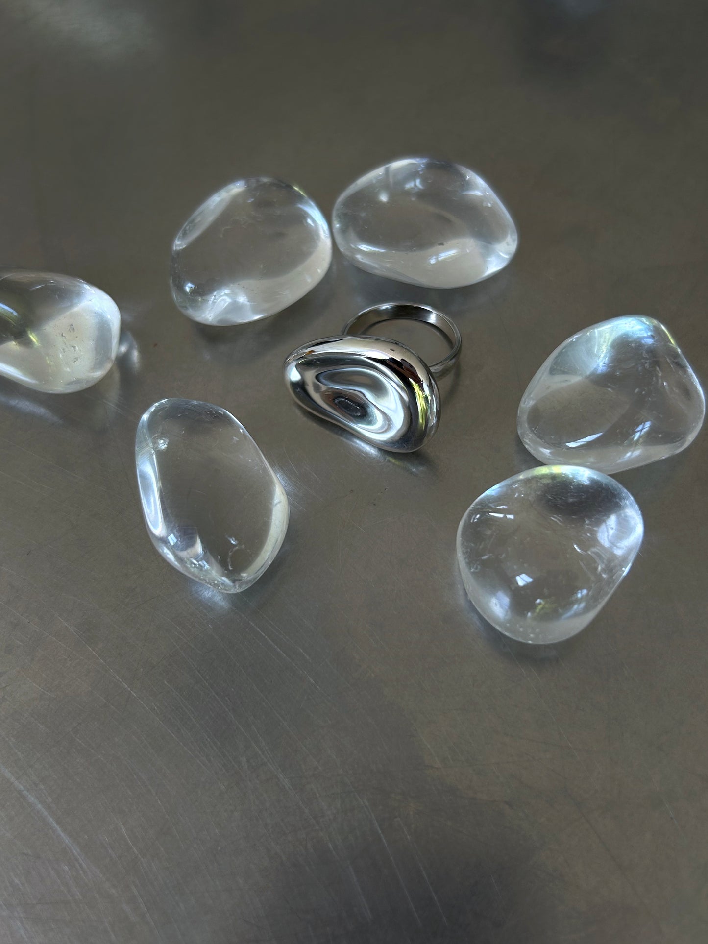 High-polish sculptural 925 silver ring surrounded by clear stones on grey background