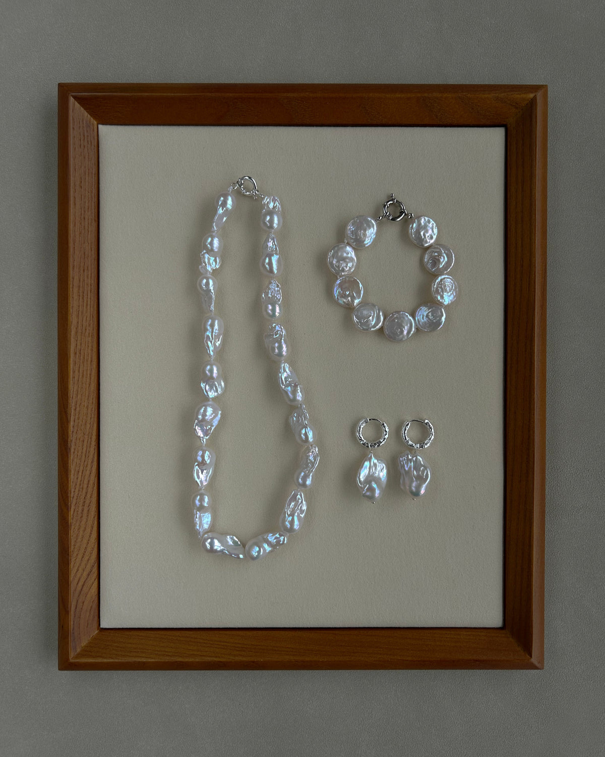 Jewelry set including a necklace, bracelet, and earrings in a wooden frame on a gray background