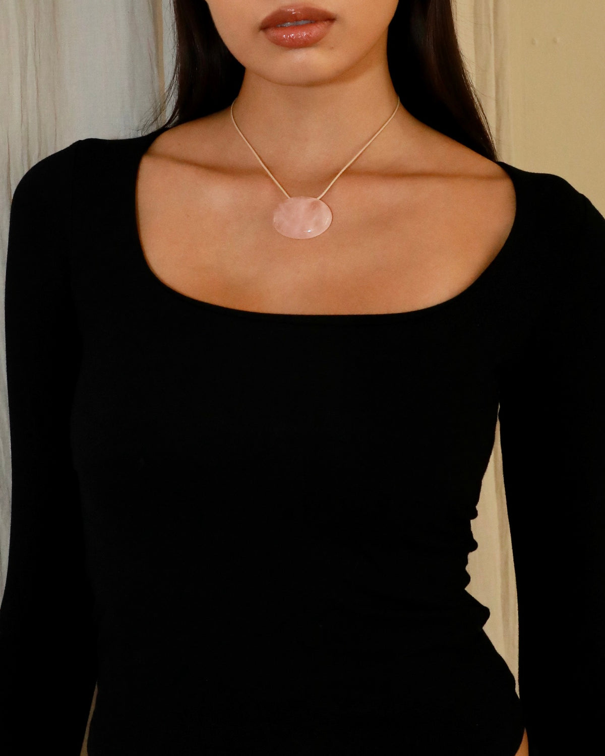 Adjustable beige cord necklace with an oval natural pink quartz pendant and black bead ends