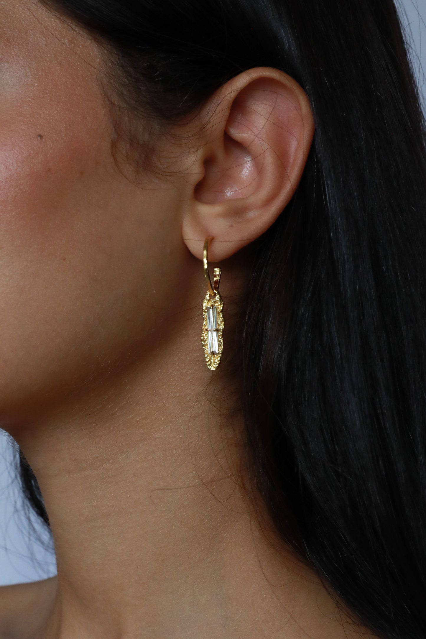 Close-up of gold plated white zircon earring on model’s ear