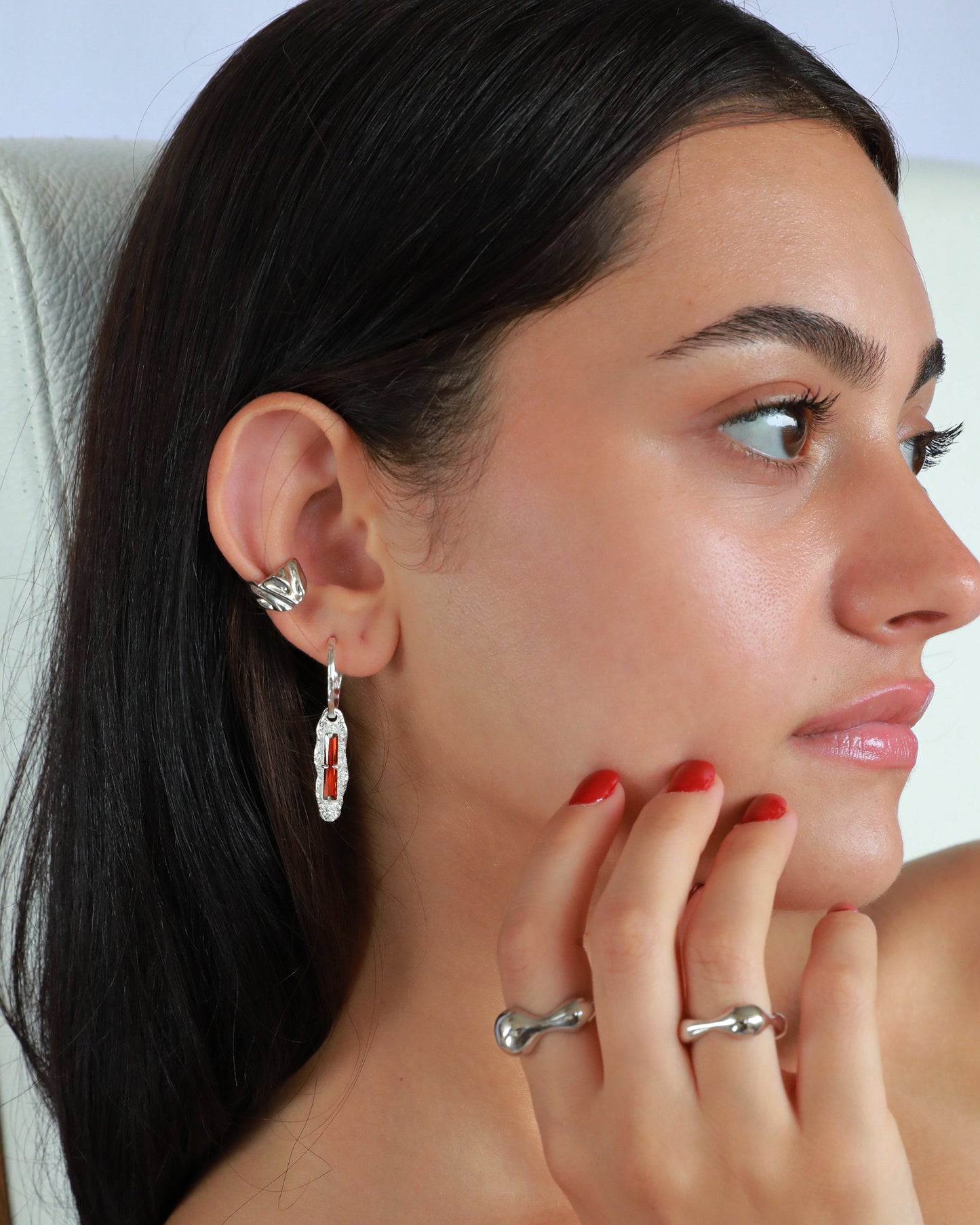 Model stacking gold ear cuff with drop zircon earrings, showing layered earring styling