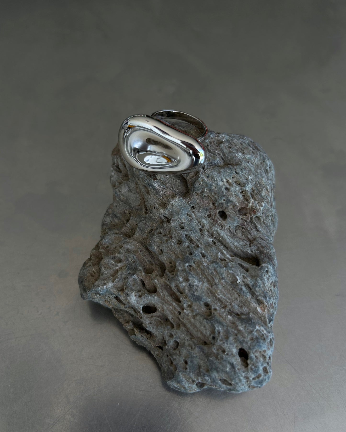 Mirror-polished dome-shaped sterling silver ring displayed on textured rock