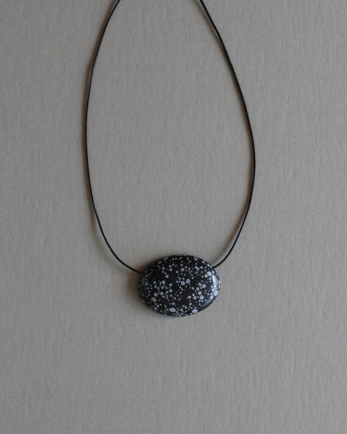 Super long snowflake obsidian pendant necklace with natural black and white speckled stone on adjustable black wax rope cord