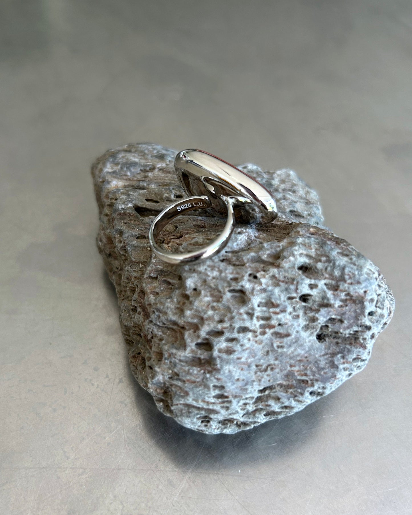 Adjustable sterling silver ring with S925 engraving on lava rock surface