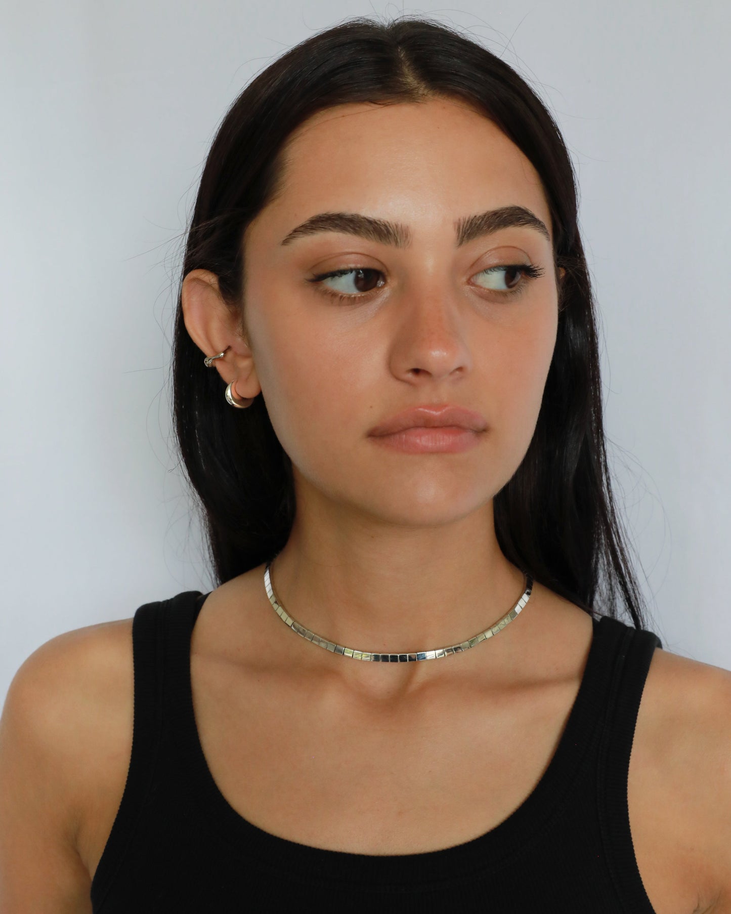Close-up of woman wearing fluid silver choker necklace with minimalist styling