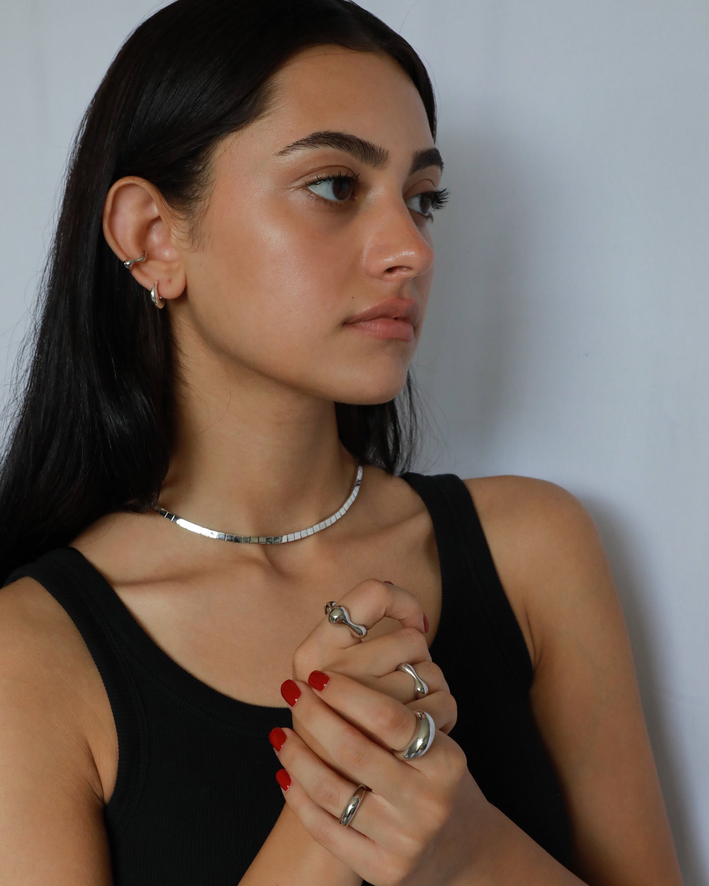 Mirror-polished silver necklace styled on model with sculptural silver rings