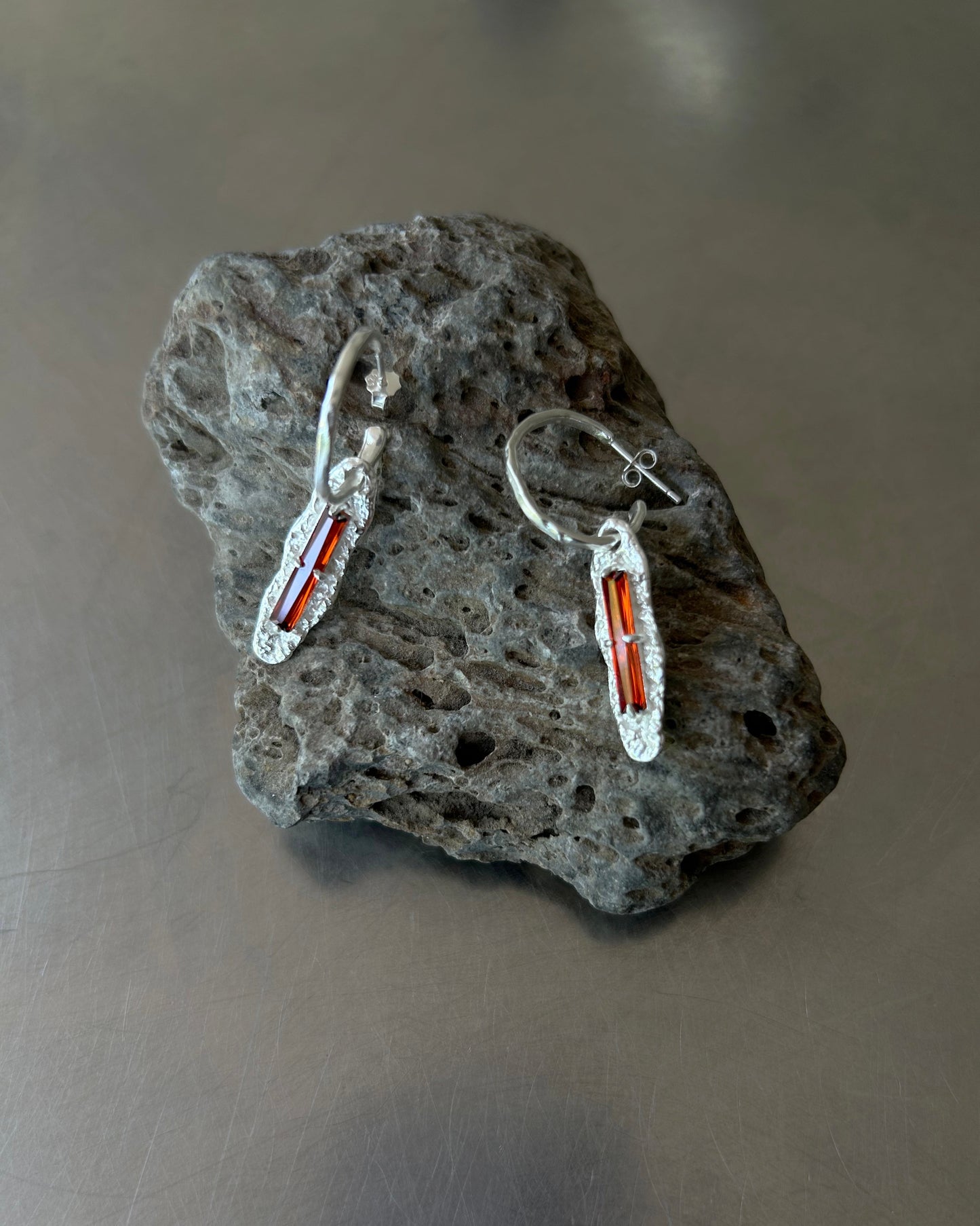 Red cubic zirconia sterling silver earrings on lava rock surface