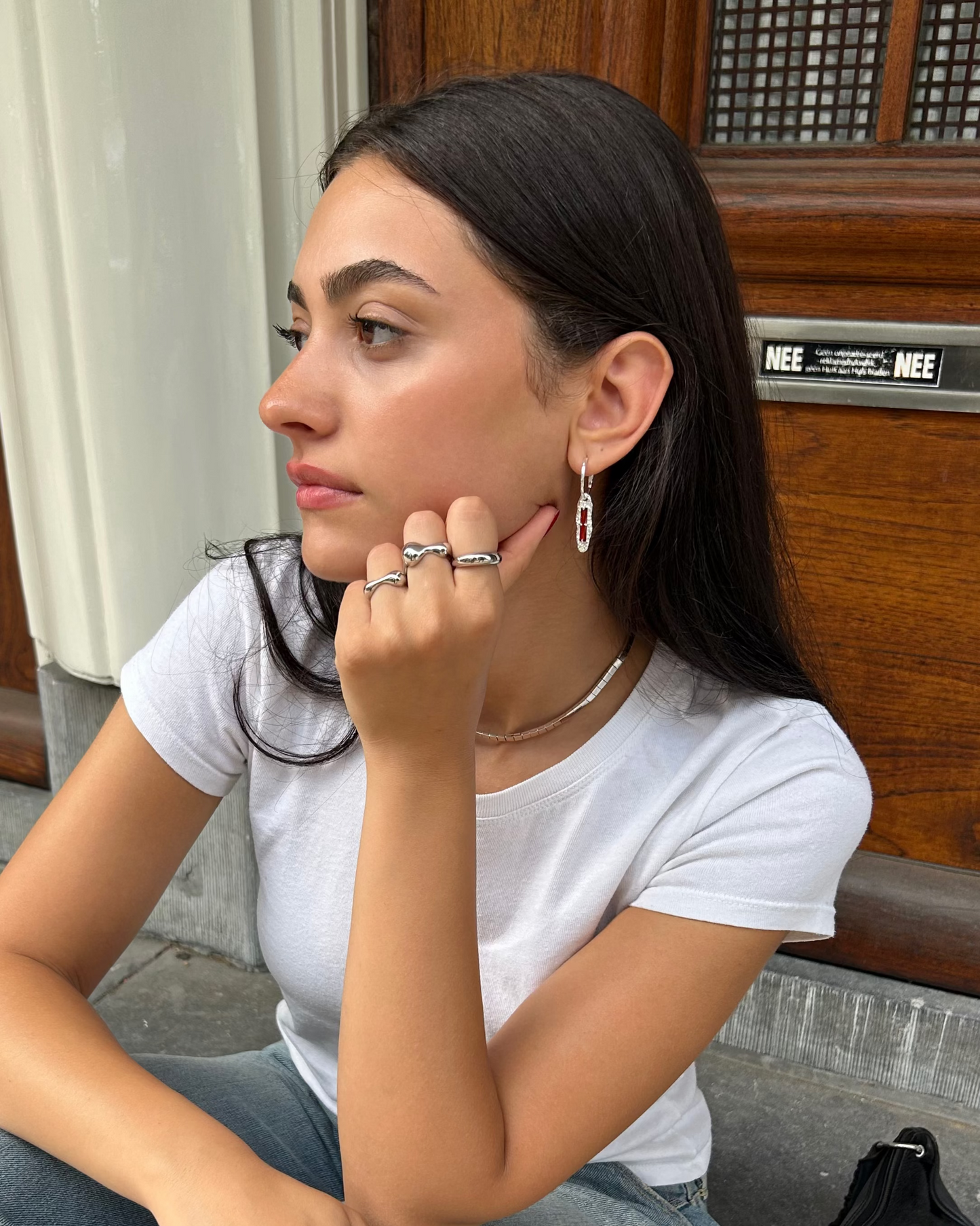 Model wearing handcrafted sterling silver earrings with red zircon in UGC style