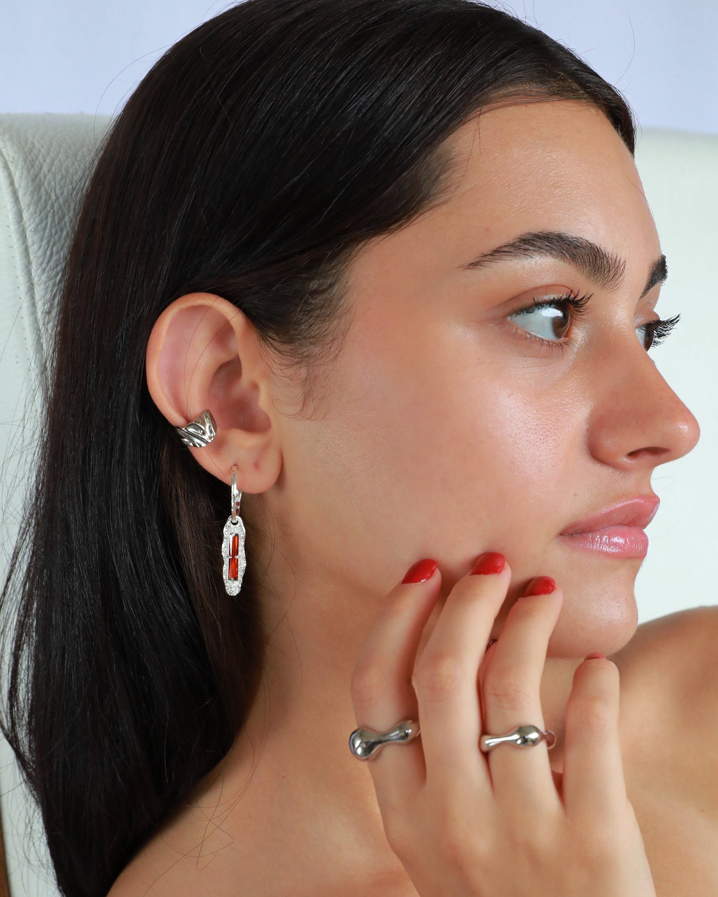 Model wearing handcrafted sterling silver earrings with red zircon