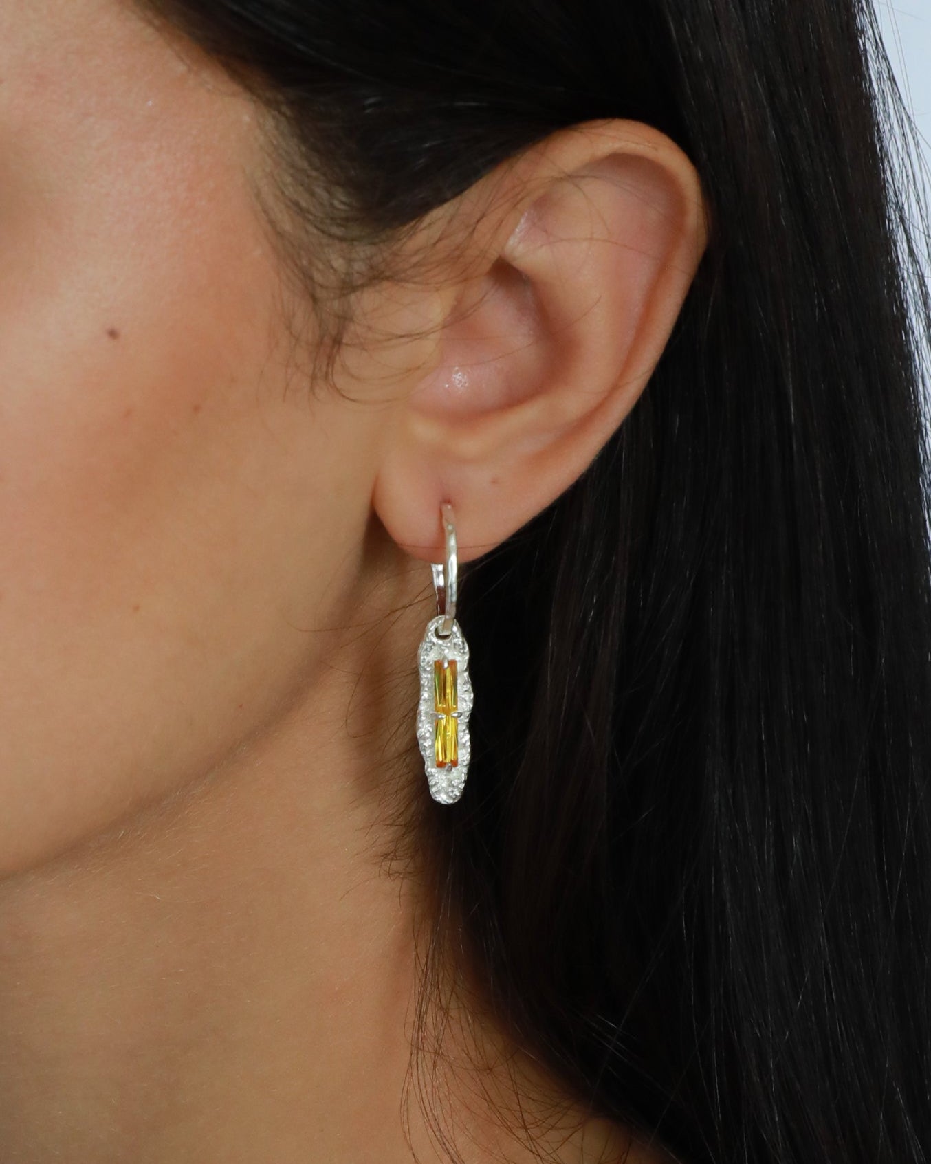 Close-up of yellow zircon drop earrings worn, highlighting closed-back bezel design