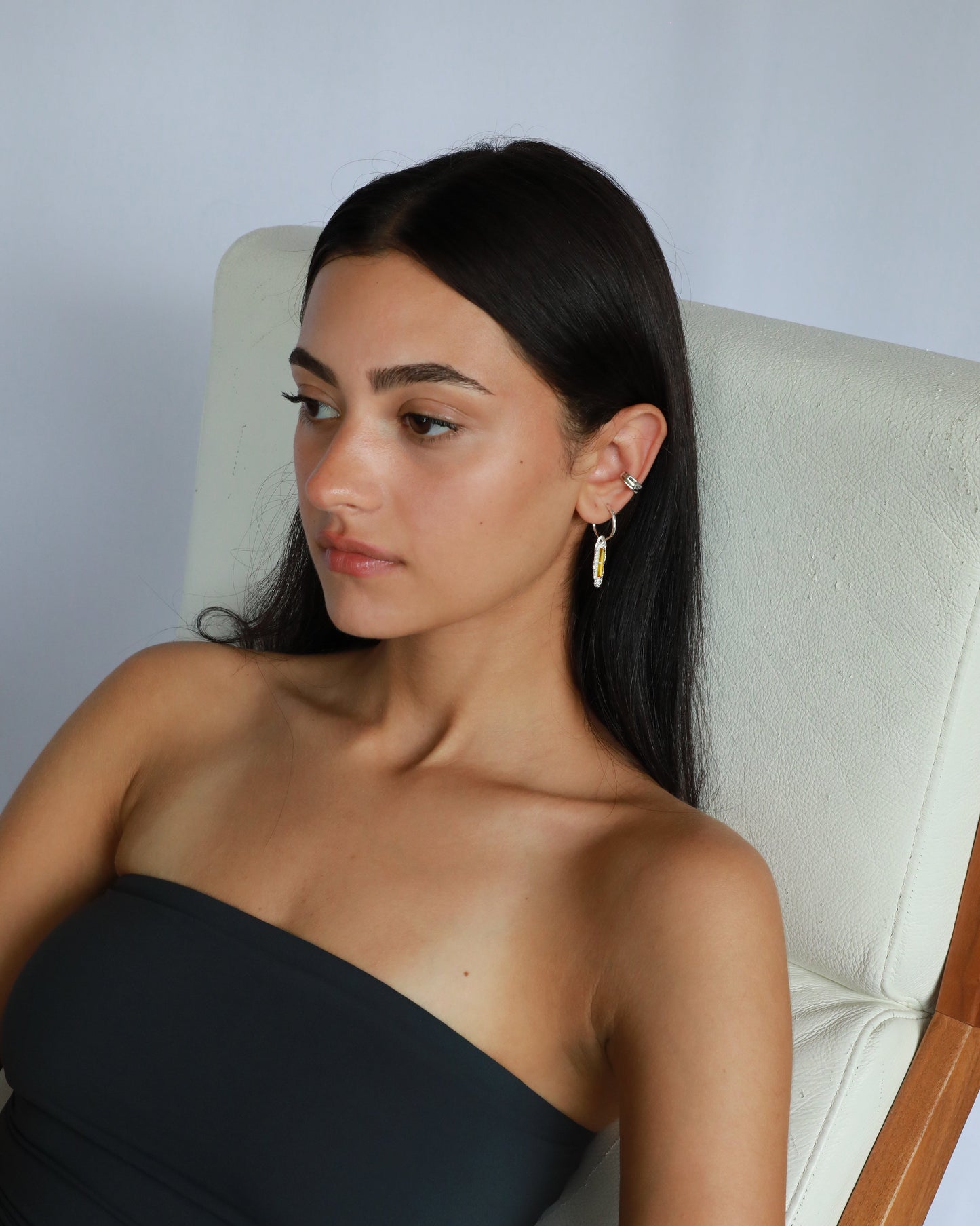 Lifestyle photo of model wearing yellow zircon sterling earrings while seated