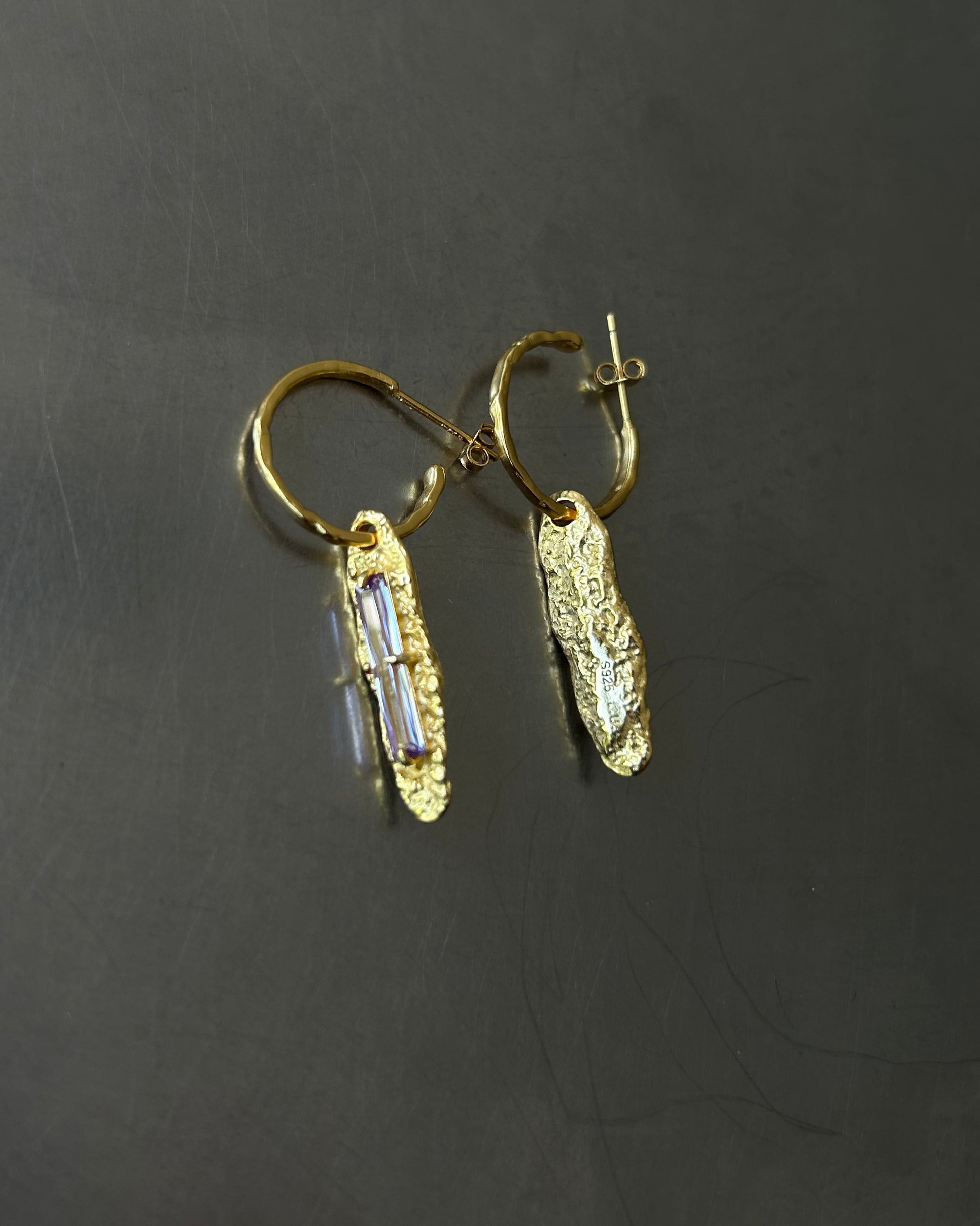 Back view of gold plated sterling silver earrings with white zircon and S925 engraving on dark background