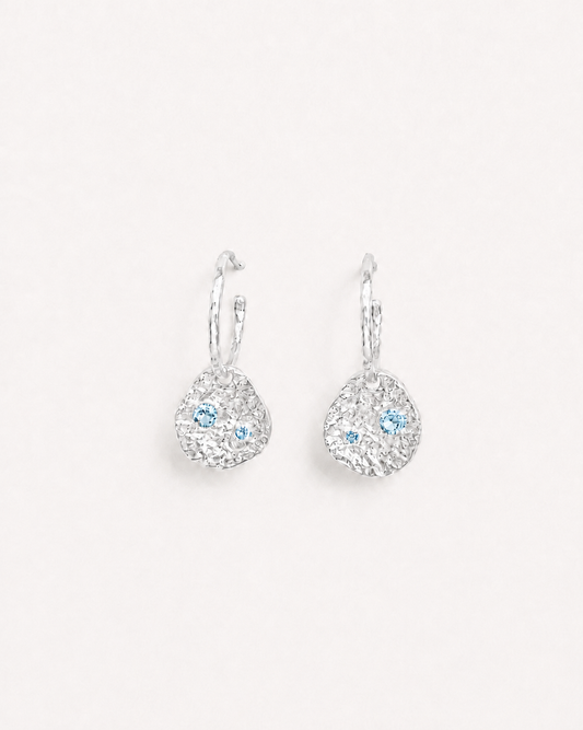 Silver coin drop earrings with hammered silver-plated brass pendants and two round lab-grown aquamarine-blue spinel stones.