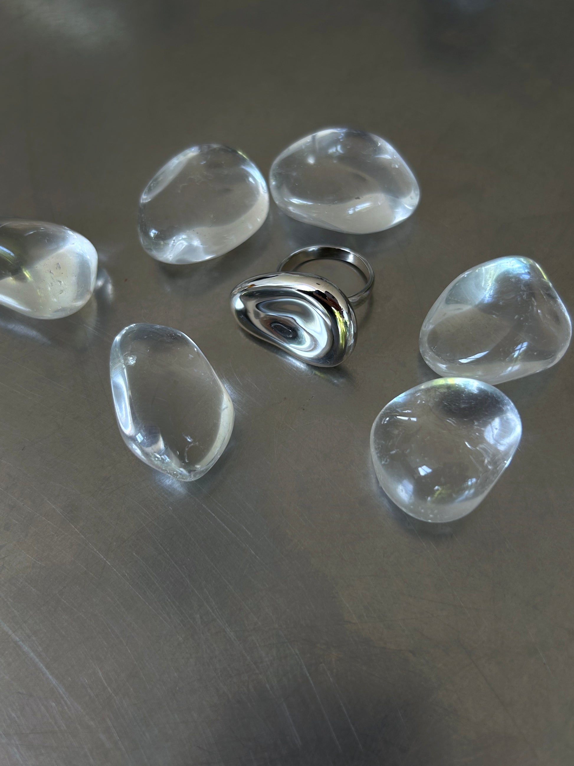 High-polish sculptural 925 silver ring surrounded by clear stones on grey background