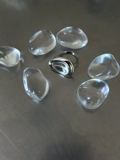 High-polish sculptural 925 silver ring surrounded by clear stones on grey background