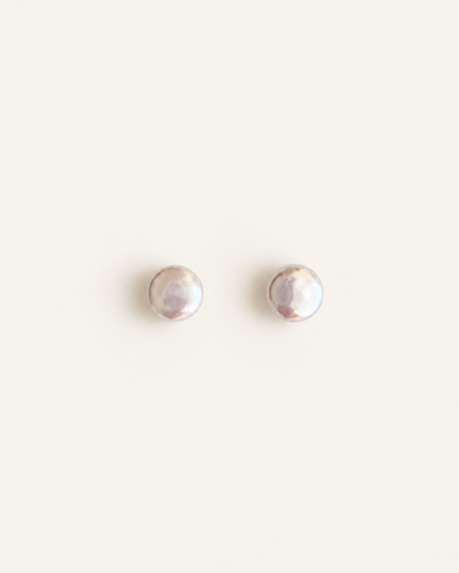 A pair of small round stud earrings with a pearlescent iridescent finish, displayed on a clean off-white background, made from natural pearls for wedding 