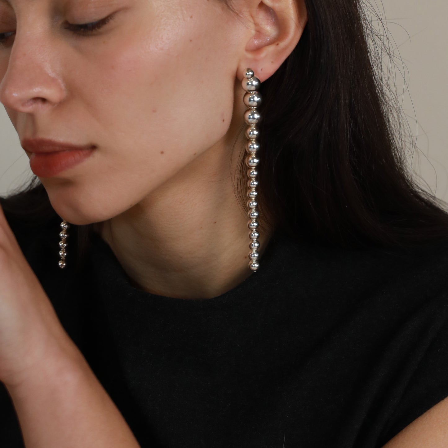 Long silver ball bead dangle earring teardrop ball chunky hoop minimalistic design earring Model close up photo