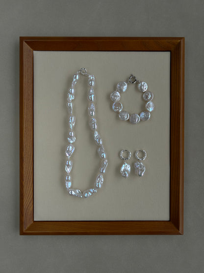 Jewelry set including a necklace, bracelet, and earrings in a wooden frame on a gray background