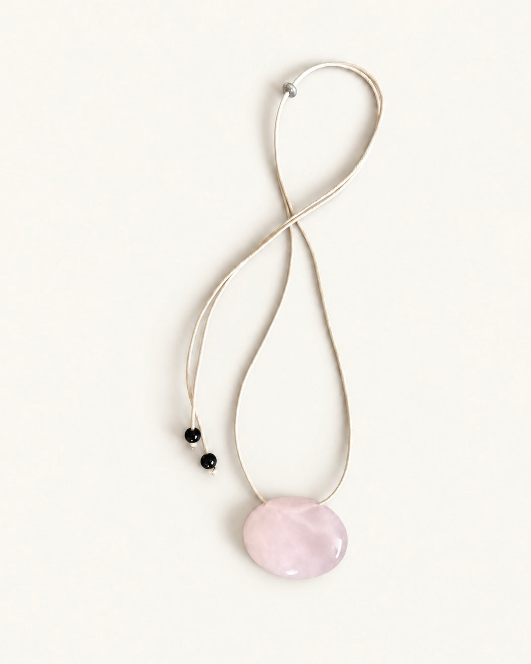 Adjustable beige cord necklace with an oval natural pink quartz pendant and black bead ends