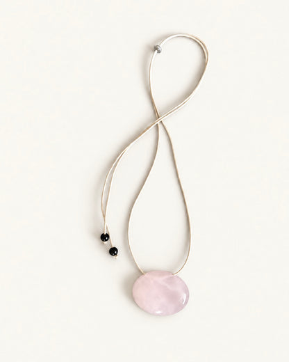 Adjustable beige cord necklace with an oval natural pink quartz pendant and black bead ends