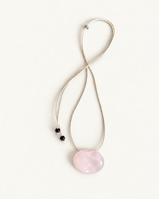 Adjustable beige cord necklace with an oval natural pink quartz pendant and black bead ends