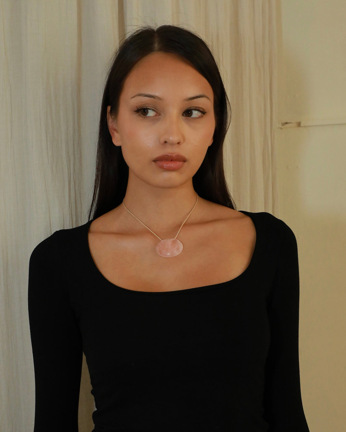 Adjustable beige cord necklace with an oval natural pink quartz pendant and black bead ends model
