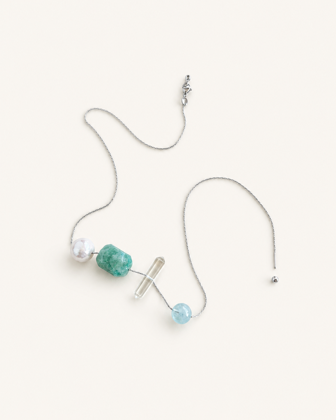 A delicate silver chain necklace with three distinct bead accents:Amazonite Clea rQuartz Aquamarine Freshwater pearls, displayed on a warm off-white background.