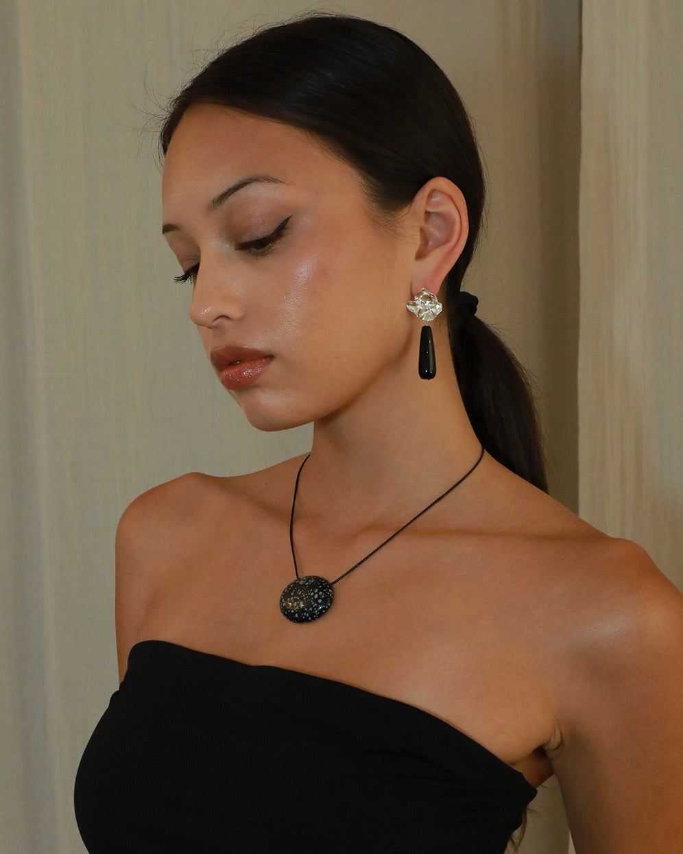 Silver-tone sculptural flower drop earrings with long polished black onyx stones on model