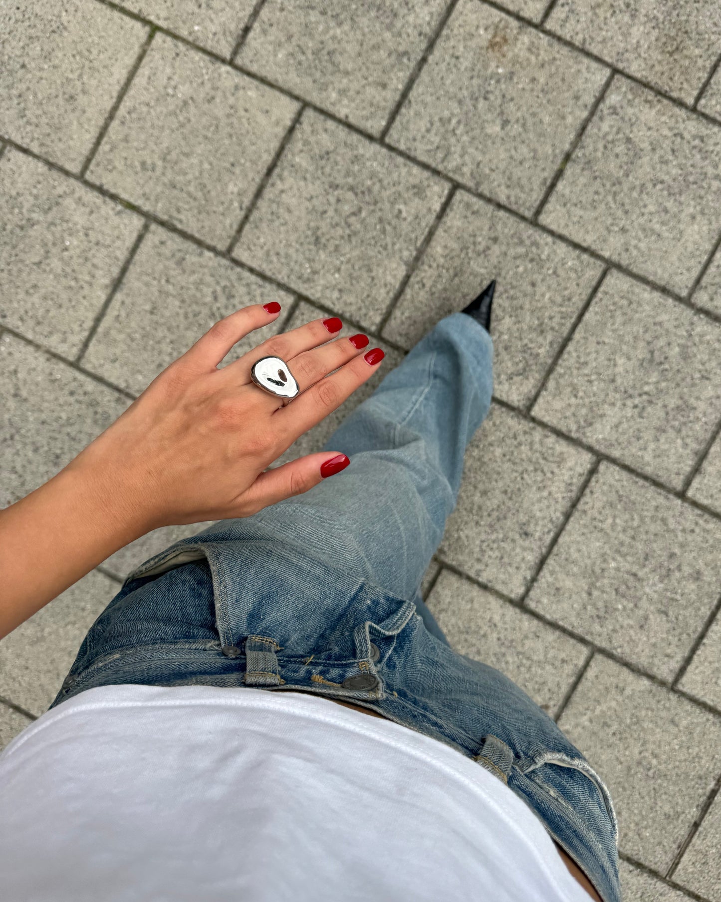 Lifestyle top-down view of silver sculptural ring styled with casual denim and white tee