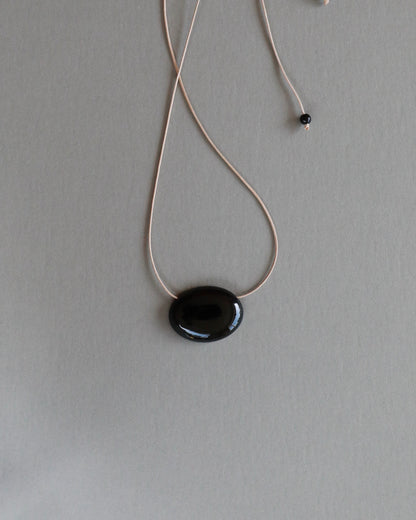 Super long adjustable necklace with polished natural black onyx pendant on soft beige cord. Minimal modern natural stone jewellery