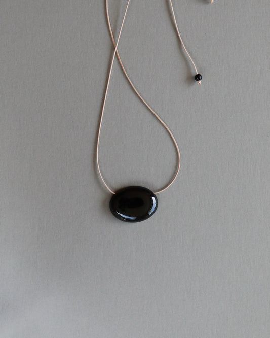 Super long adjustable necklace with polished natural black onyx pendant on soft beige cord. Minimal modern natural stone jewellery