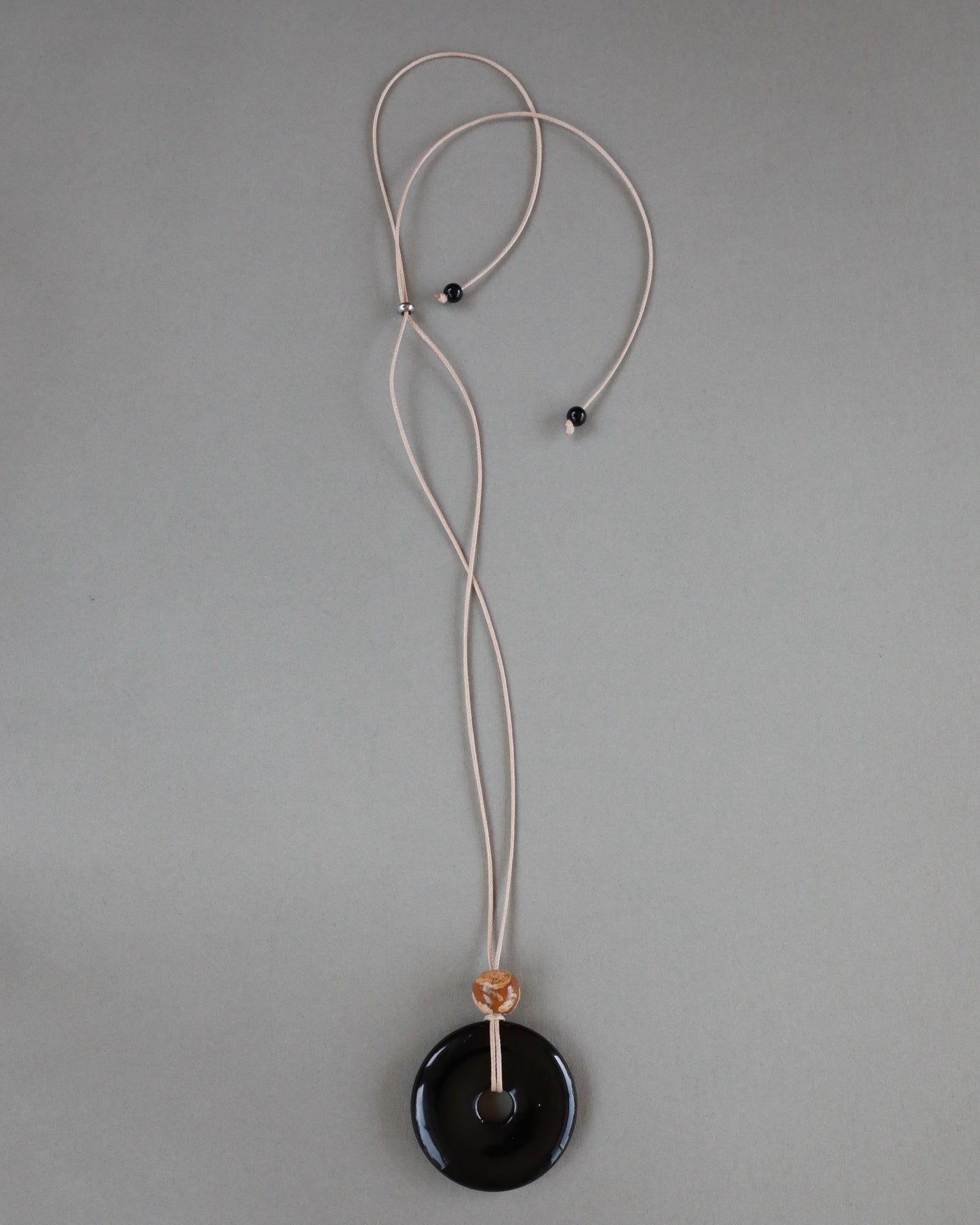 Super long adjustable necklace with polished black onyx pendant, natural picture jasper bead, and beige wax rope cord.