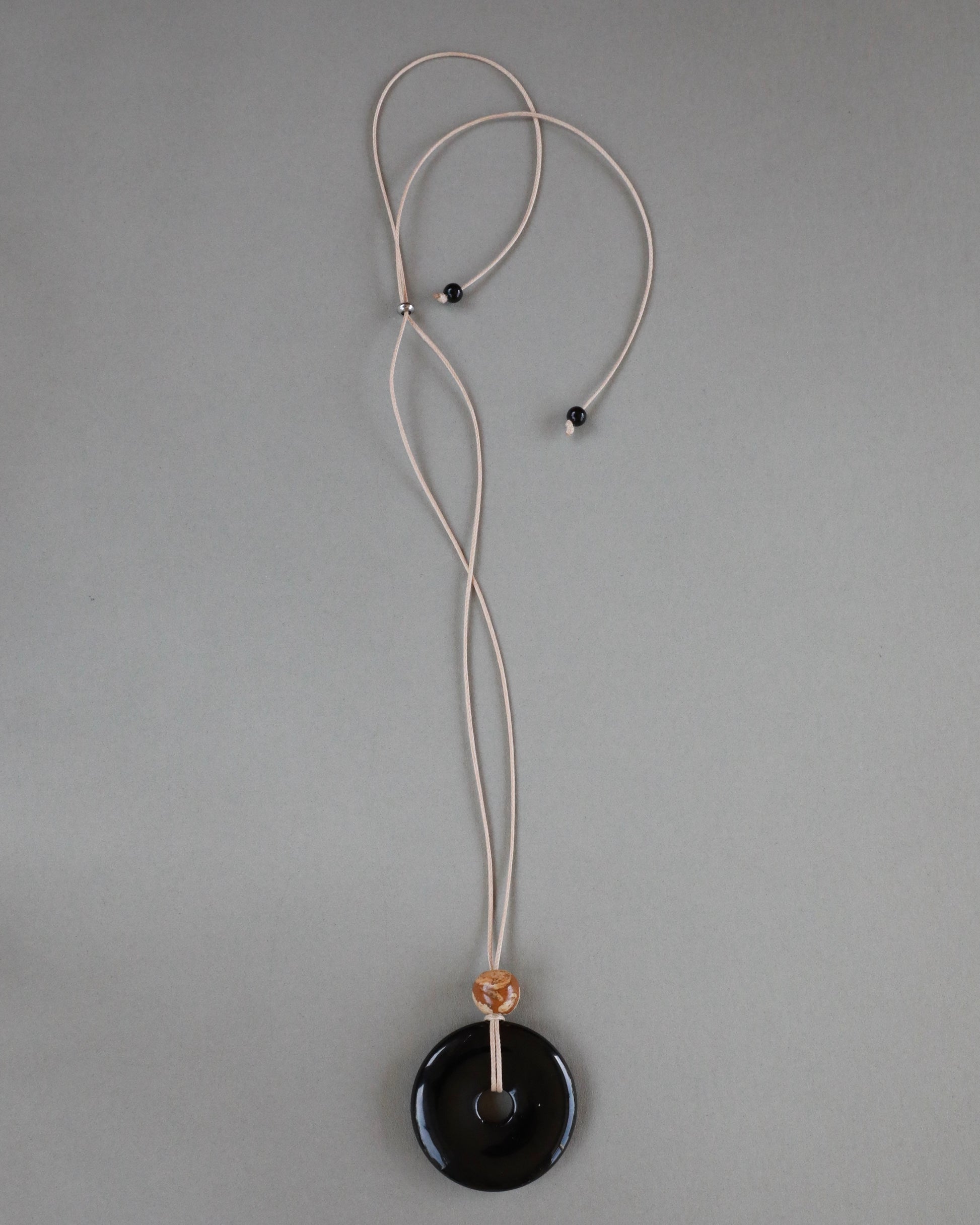 Super long adjustable necklace with polished black onyx pendant, natural picture jasper bead, and beige wax rope cord.