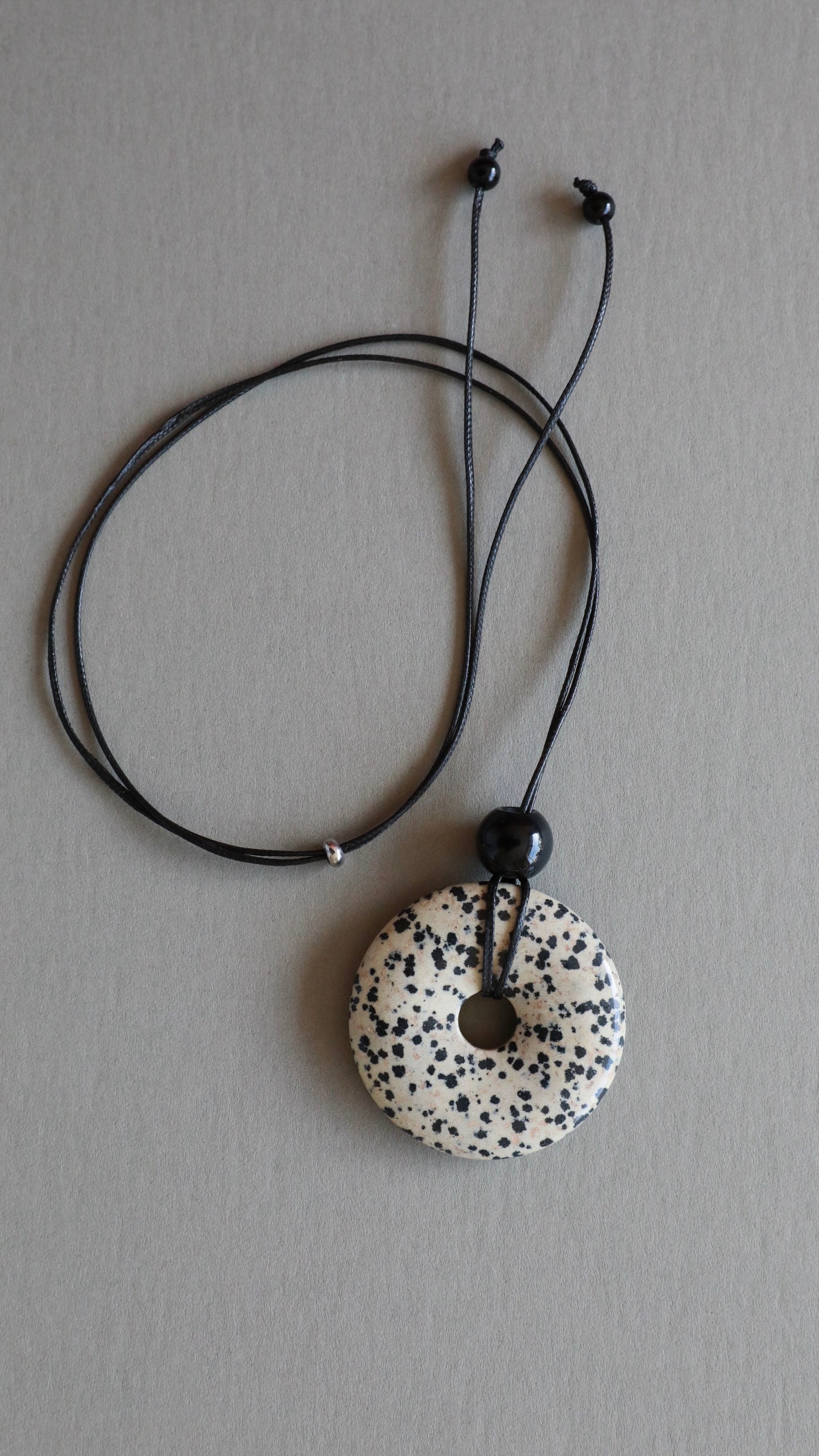 Super long dalmatian jasper pendant necklace with natural black and white spotted stone on adjustable black wax rope cord.