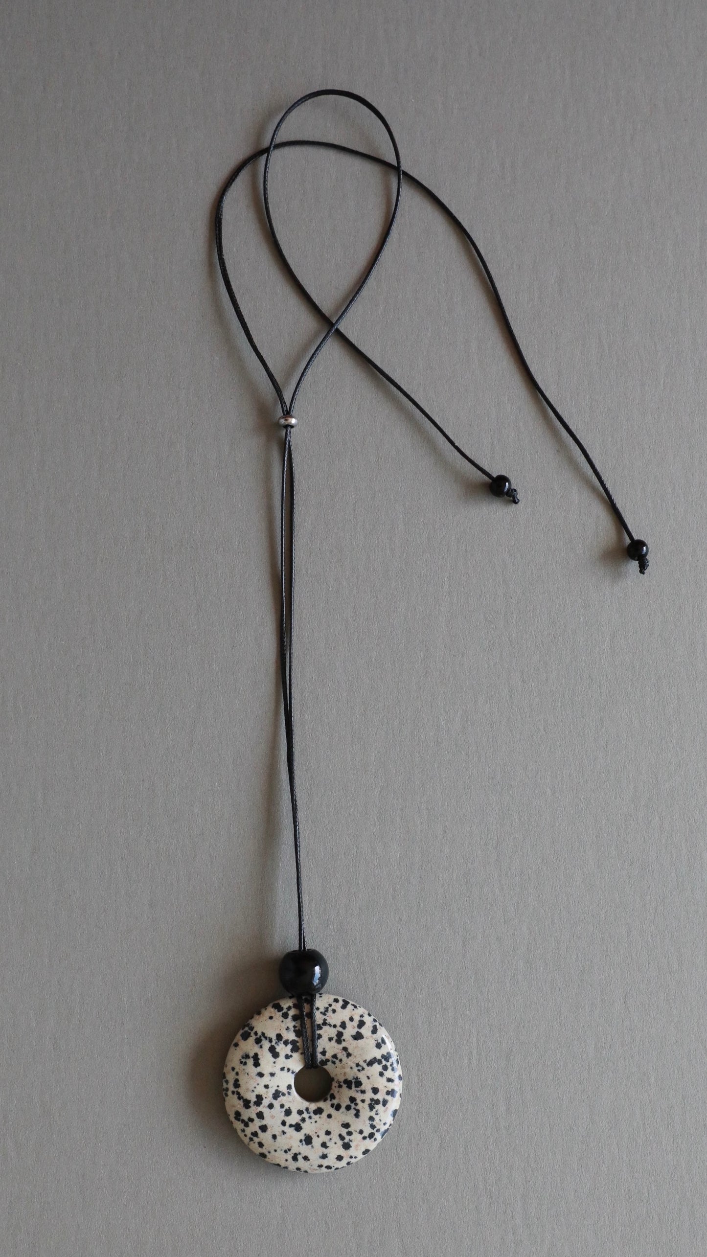 Super long dalmatian jasper pendant necklace with natural black and white spotted stone on adjustable black wax rope cord.