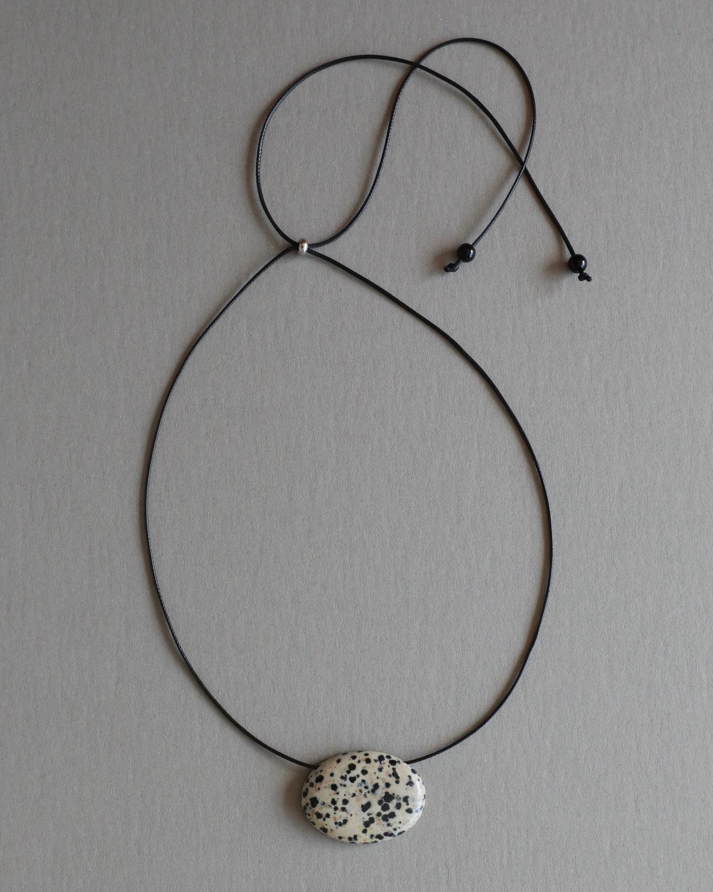 Super long dalmatian jasper pendant necklace with natural black and white spotted stone on adjustable black wax rope cord