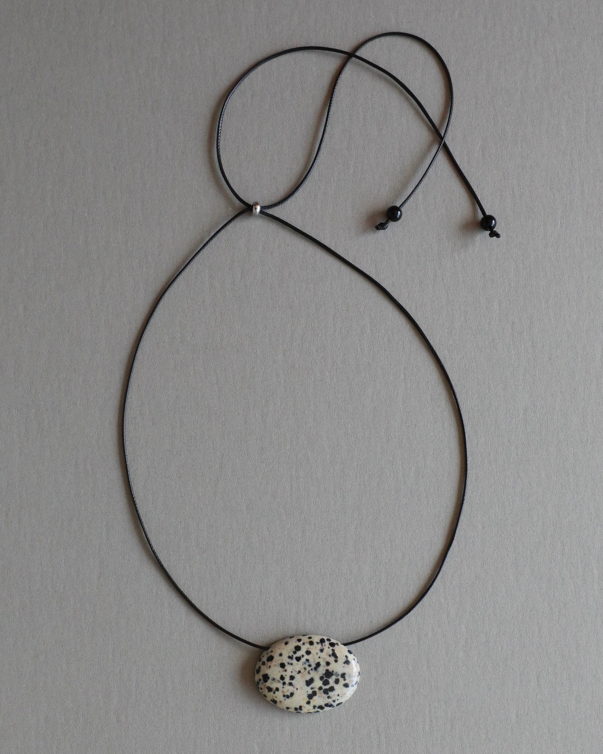 Super long dalmatian jasper pendant necklace with natural black and white spotted stone on adjustable black wax rope cord