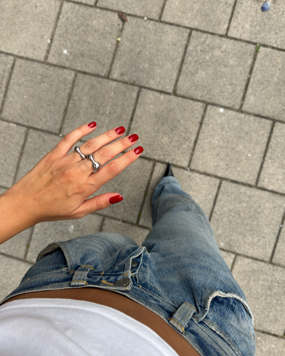 Overhead shot of stacked sculptural silver rings on fingers, showcasing fluid shapes