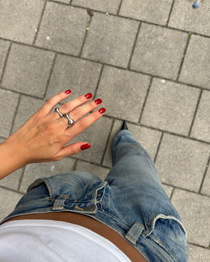 Overhead shot of stacked sculptural silver rings on fingers, showcasing fluid shapes