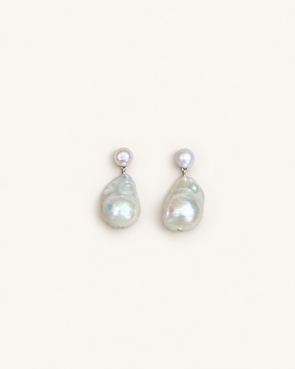 A pair of baroque pearl drop earrings with small round pearl studs on silver-toned posts, displayed against a solid off-white background.