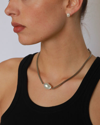 Close-up of a woman wearing a pearl necklace and earrings against a neutral background