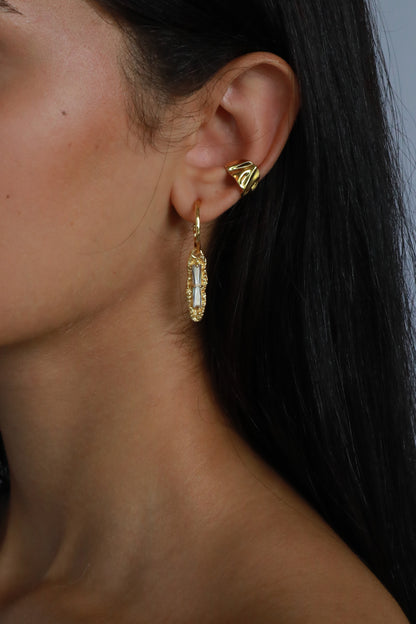 Close-up of 18k gold plated white zircon earring on model’s ear styled with gold ear cuff