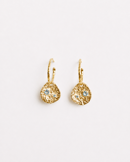 Gold coin drop earrings with hammered 18K gold-plated brass pendants and two round lab-grown aquamarine-blue spinel stones 