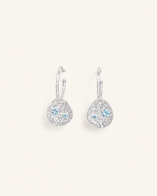Silver coin drop earrings with hammered silver-plated brass pendants and two round lab-grown aquamarine-blue spinel stones.