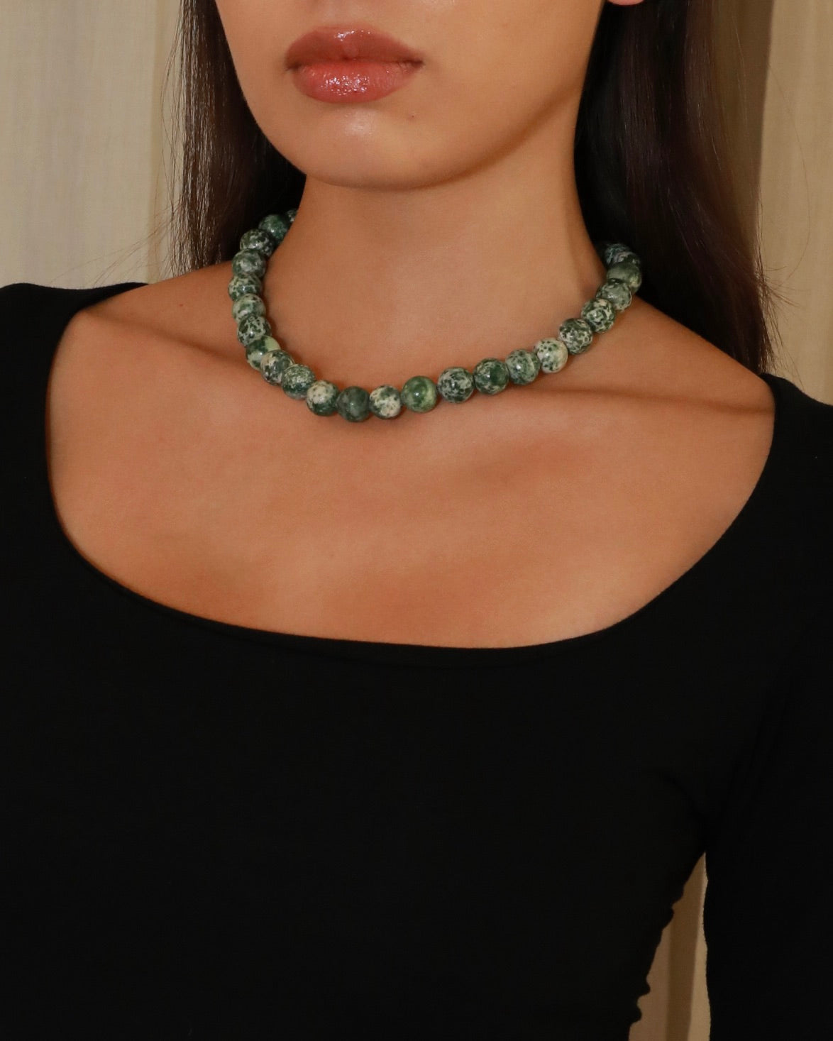 Natural green spot stone beaded necklace with green and white patterned beads model close up 