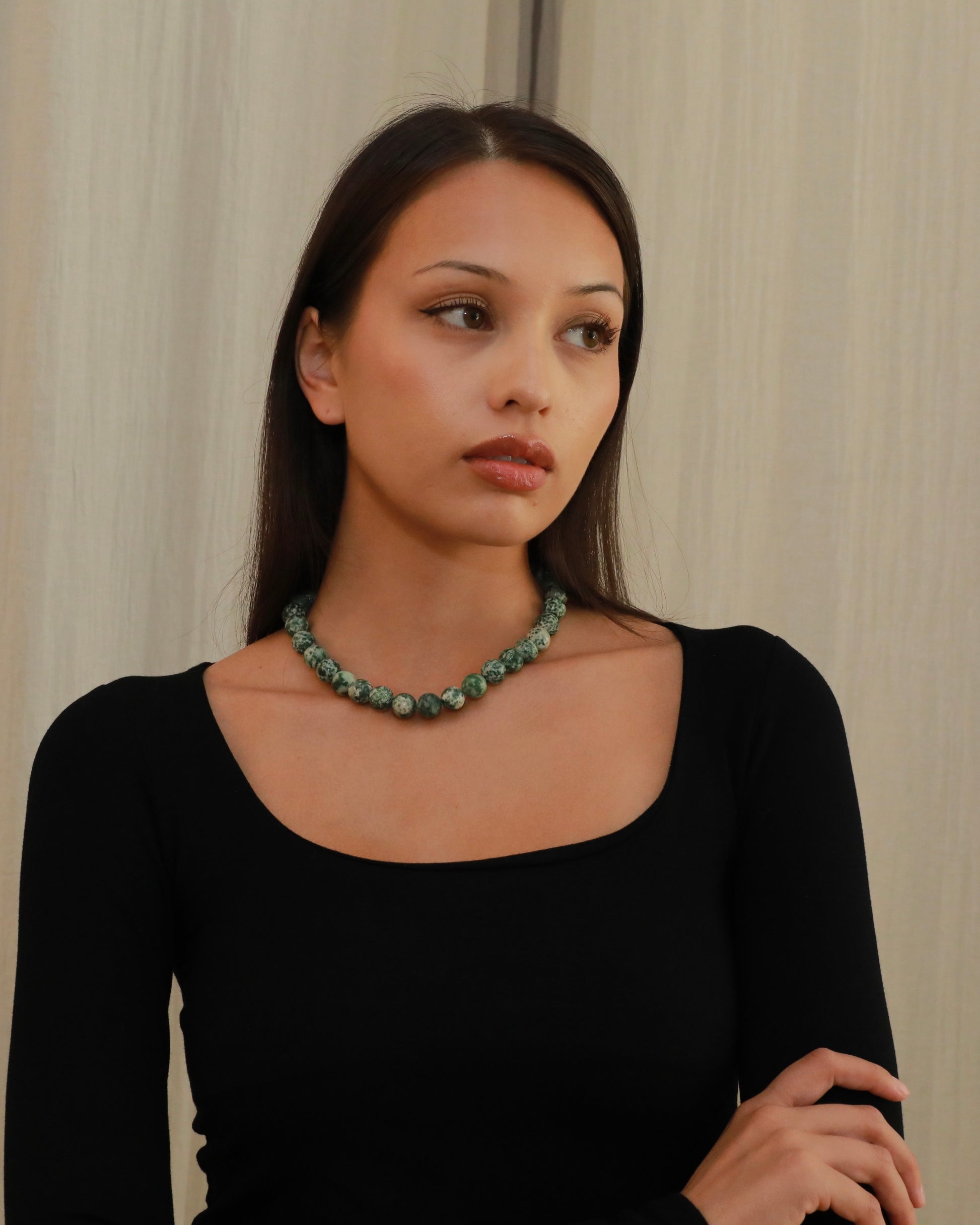 Natural green spot stone beaded necklace with green and white patterned beads model close up 