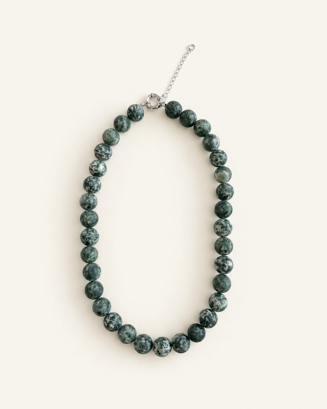 Natural green spot stone beaded necklace with green and white patterned beads and silver clasp.