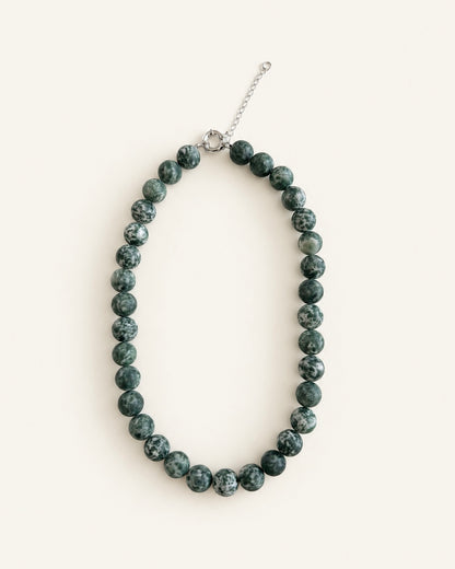 Natural green spot stone beaded necklace with green and white patterned beads and silver clasp.